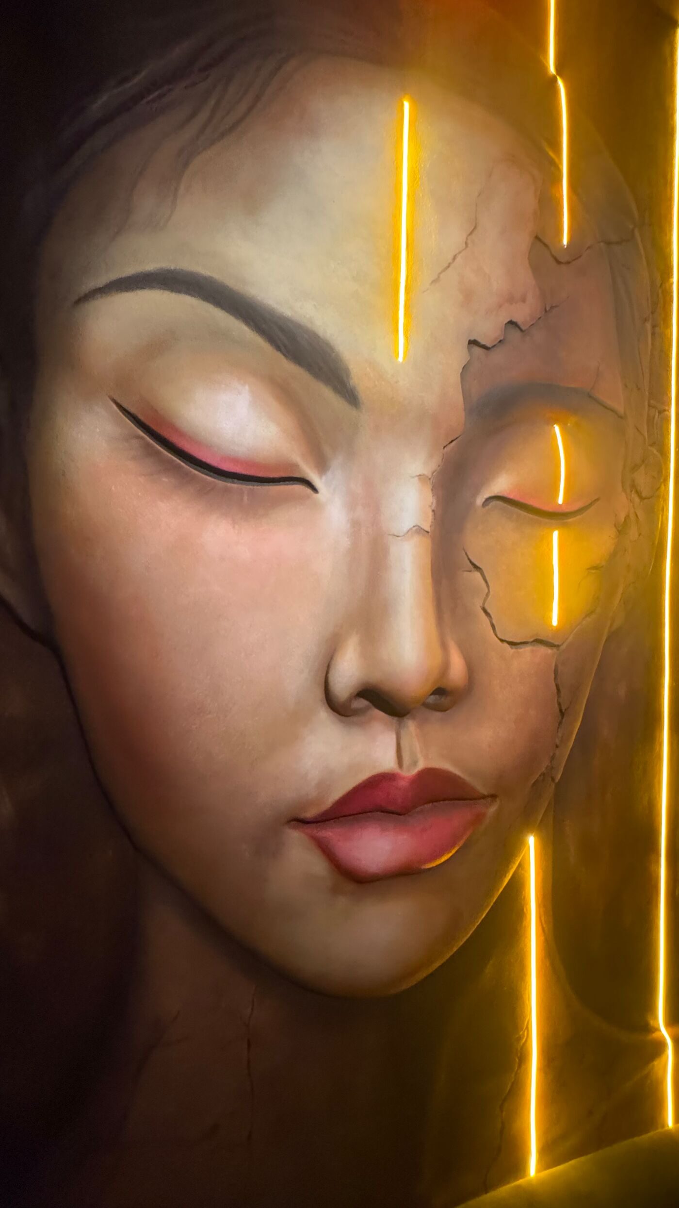 Detail: closed eye of a painted face with golden lines of light.