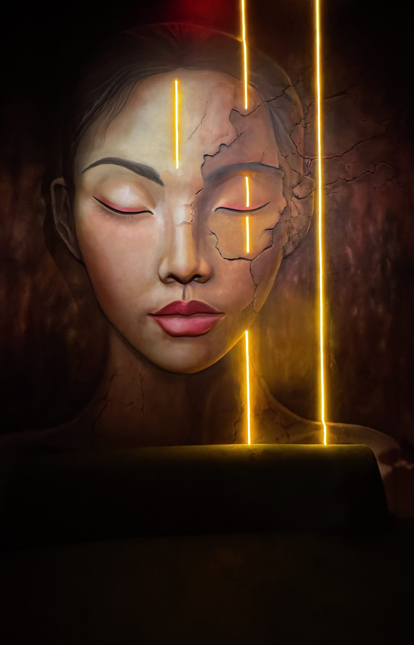 The complete wall at Yamashiro Restaurante: a face in relief with a cracked surface, crossed by vertical lines of warm LED light.